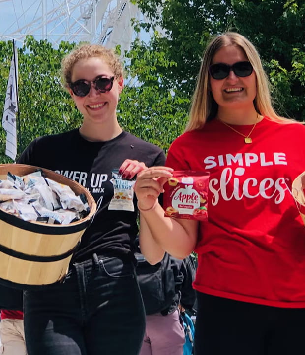 Power Up Premium Trail Mix and Simple Slices employees holding their respective snacks